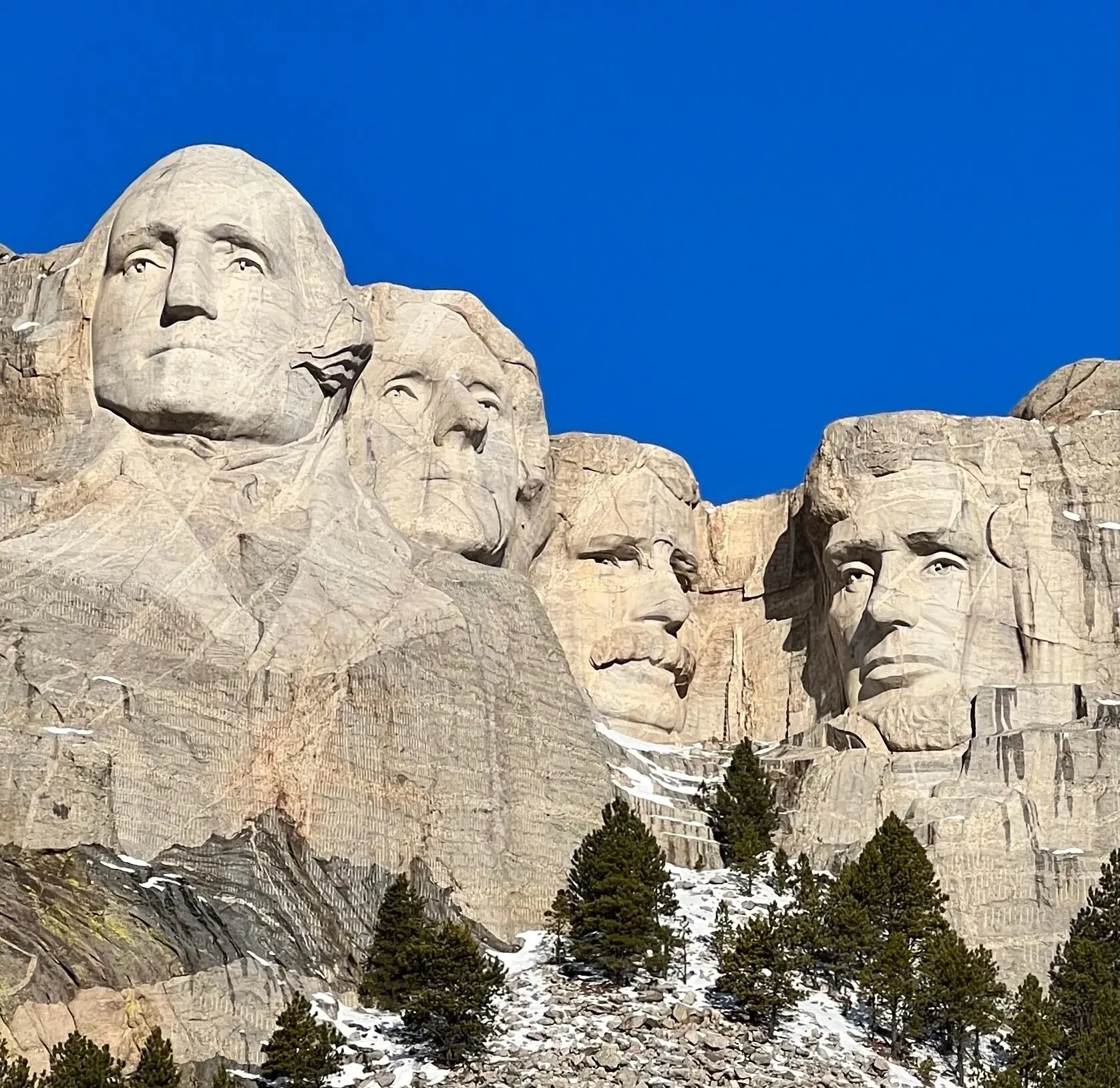 The four presidential faces of Mount Rushmore, Washington, Jefferson, Roosevelt and Lincoln, under a clear blue sky