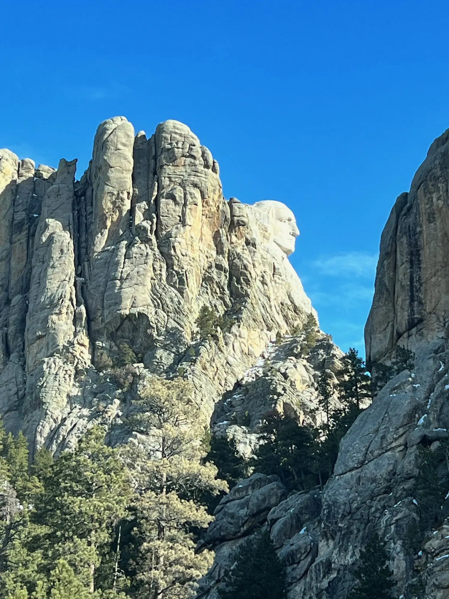 George Washington's profile carved into Mount Rushmore, glimpsed through a gap in granite rock spires