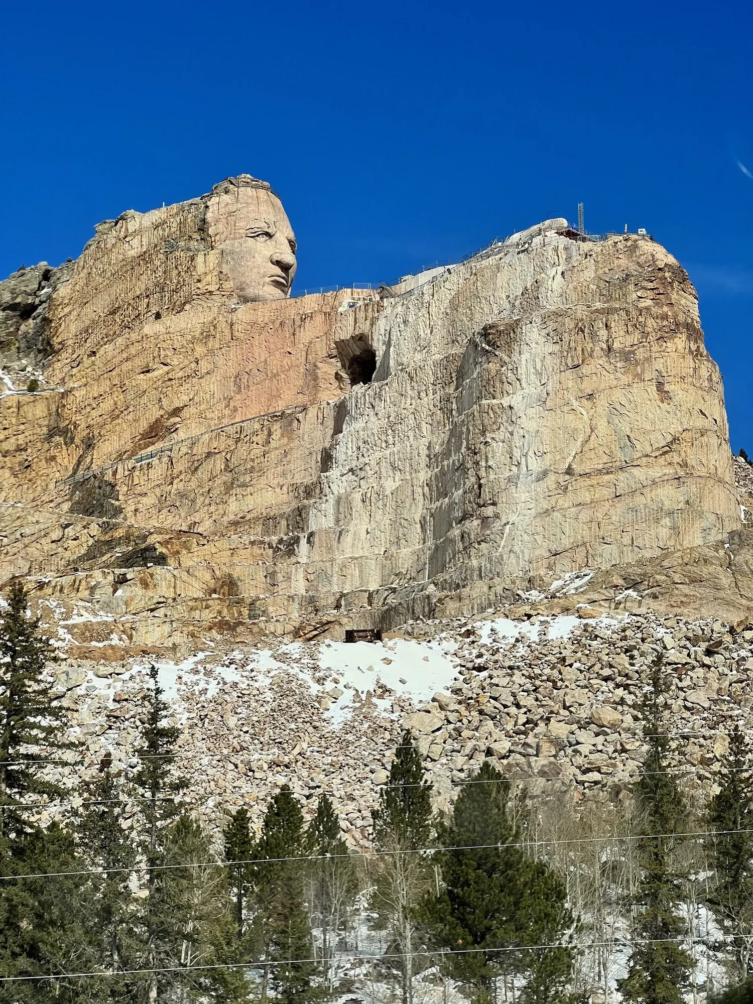 The Crazy Horse Memorial mountain, showing the completed face above a vast expanse of unfinished granite