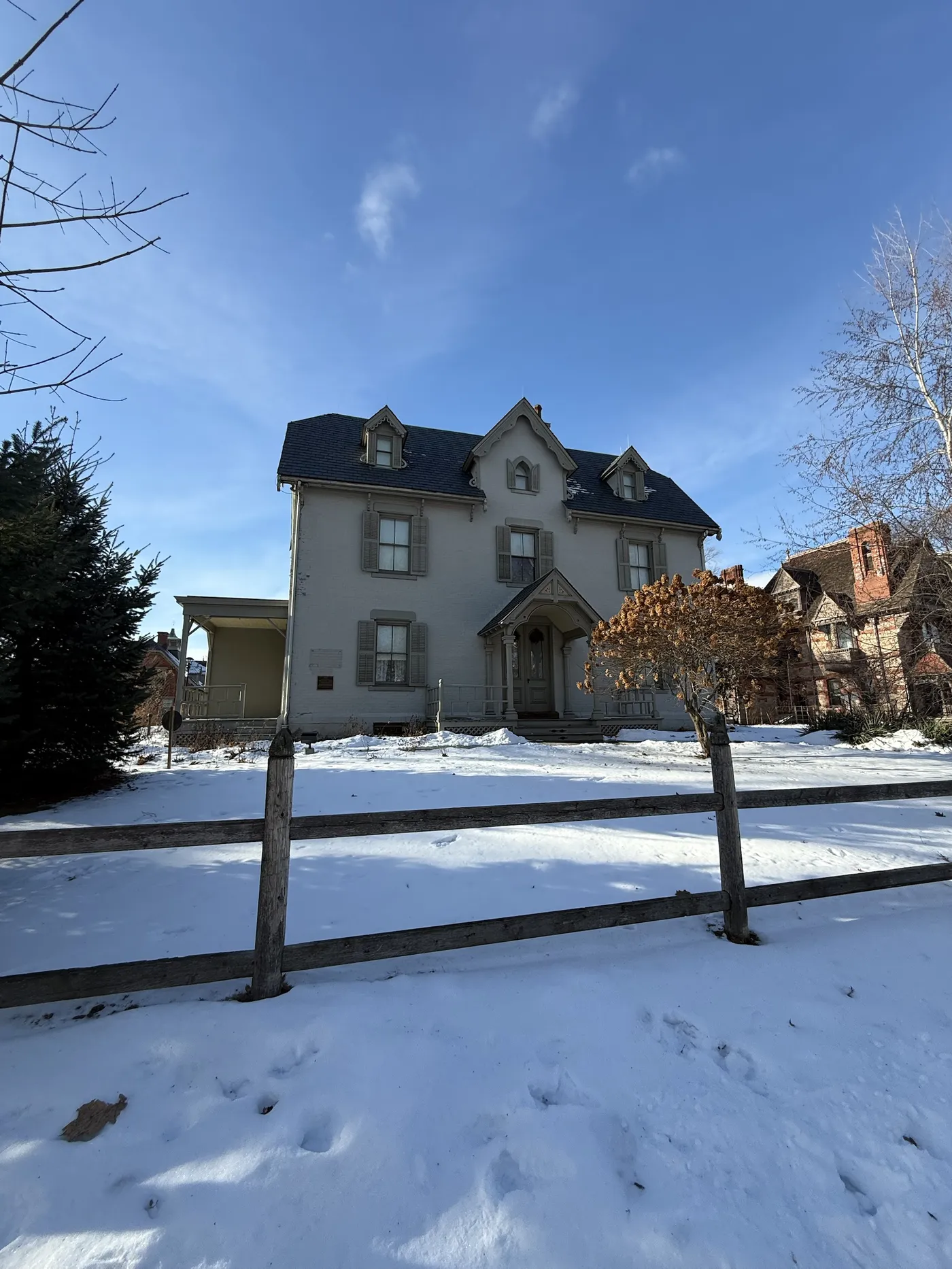 The Harriet Beecher Stowe House in Hartford, a gray Gothic Revival home in the snow, with the red brick Mark Twain House visible at right