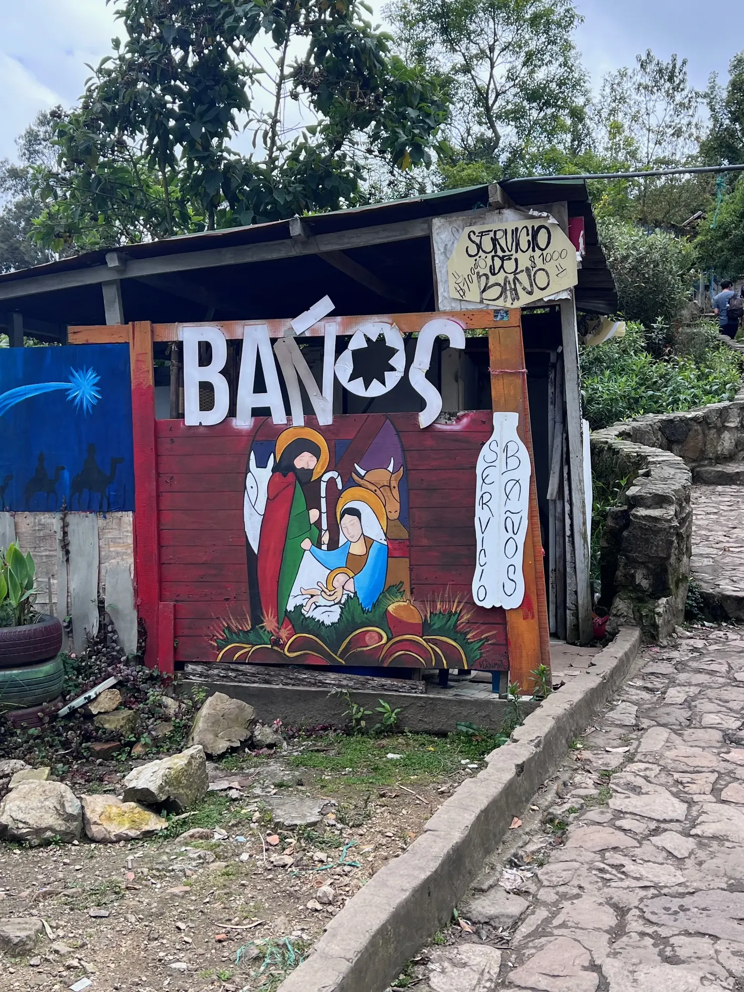 Hand-painted restroom sign with a nativity scene behind Monserrate's church